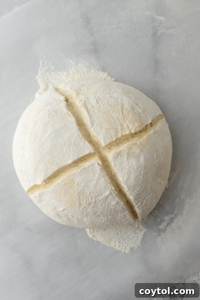 A freshly scored sourdough boule, showcasing a beautiful, intricate design on its surface before baking.