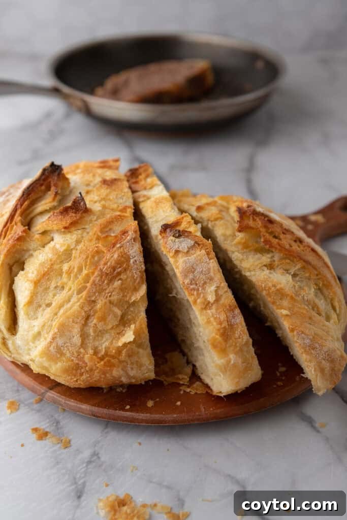 A beautifully sliced loaf of Croissant Sourdough Bread, with individual pieces arranged to show off its enticing texture and golden crust.