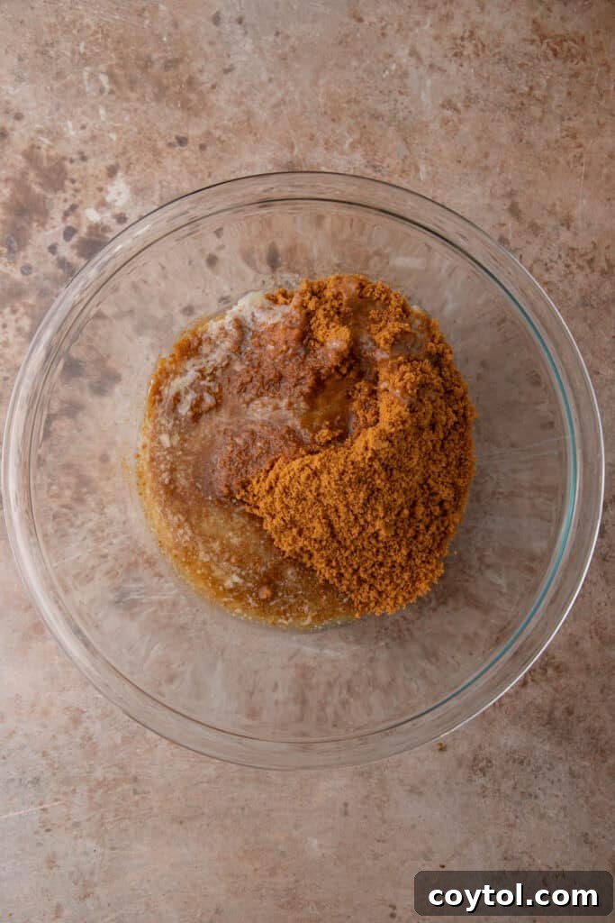 Unlock the Secret to the Perfect Biscoff Pie Crust 6 Melted butter being poured over Biscoff cookie crumbs in a mixing bowl.