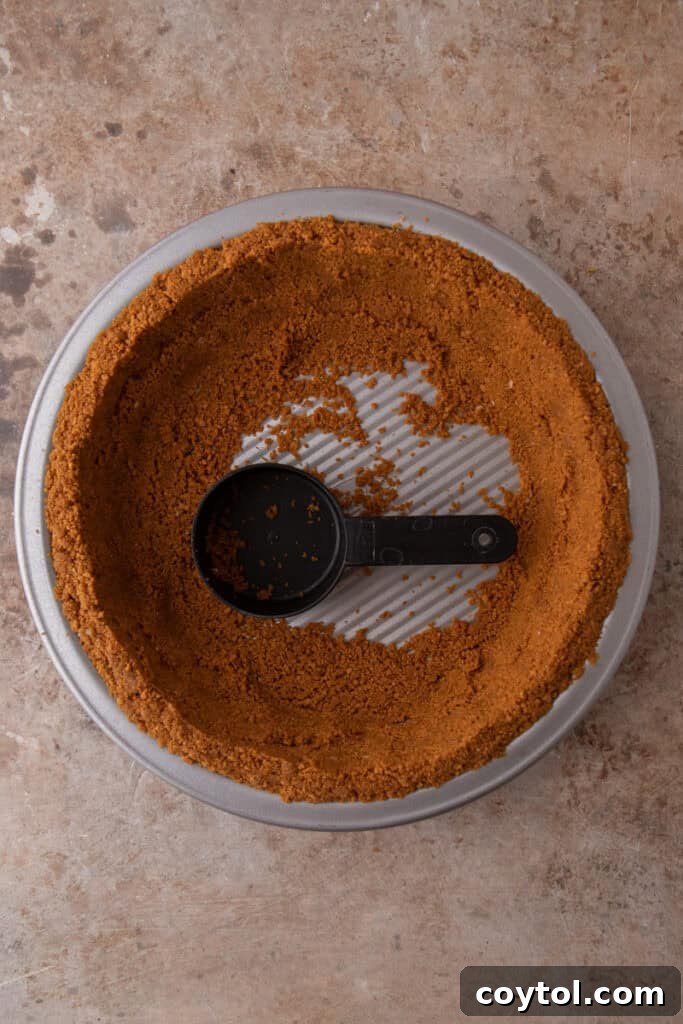 Unlock the Secret to the Perfect Biscoff Pie Crust 8 Biscoff crumbs being pressed firmly up the sides of a pie plate with the back of a spoon.