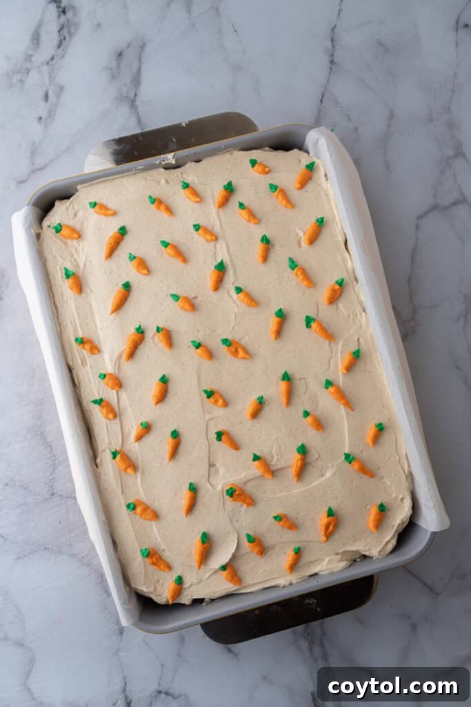 Baked carrot cake in a pan with smooth brown butter frosting spread over the top