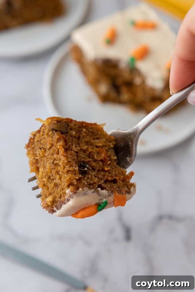 A fork holding a piece of Carrot Cake Sheet Cake, ready for a bite