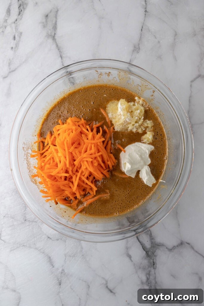 Another angle of unmixed wet ingredients in a bowl, showcasing the vibrant carrots