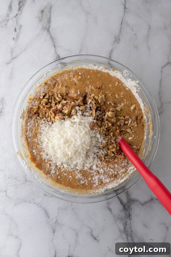 Mid-mixing stage of the carrot cake batter, showing dry and wet ingredients combining