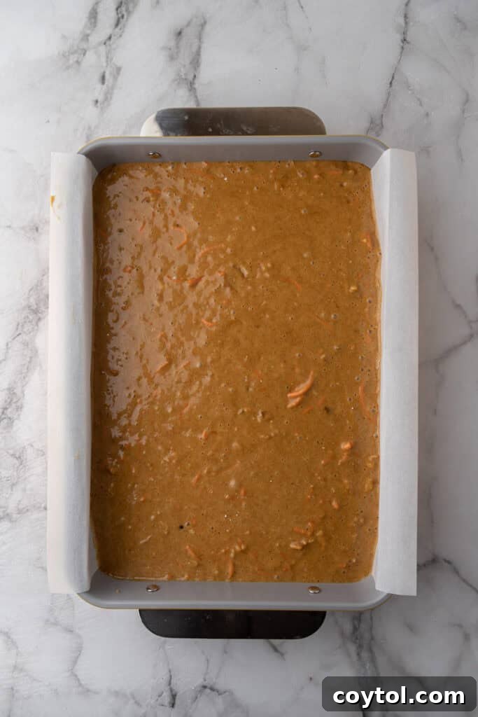 Carrot cake batter poured into a 9x13 inch baking pan, ready for the oven