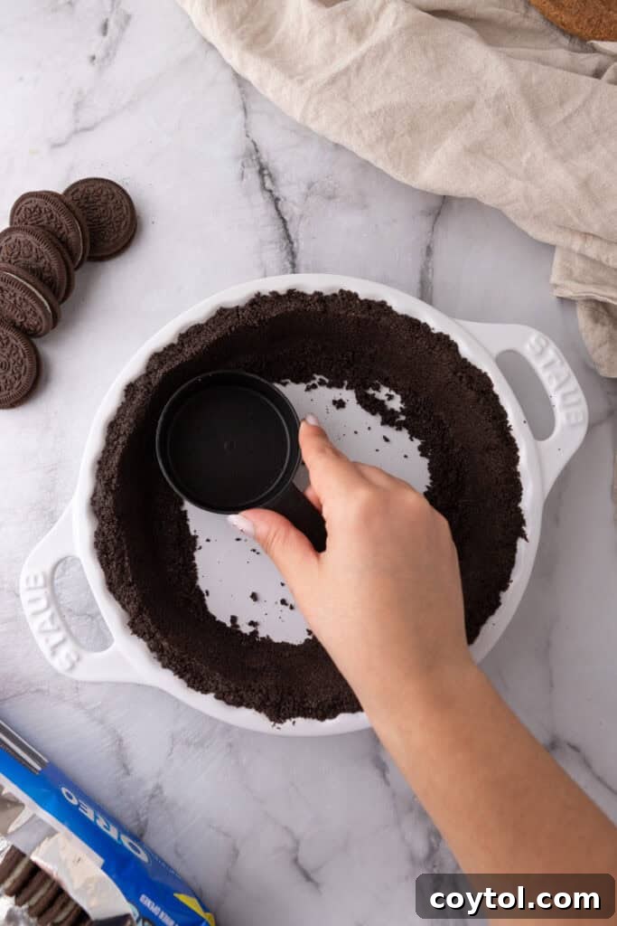 Oreo pie crust being pressed into a pie dish