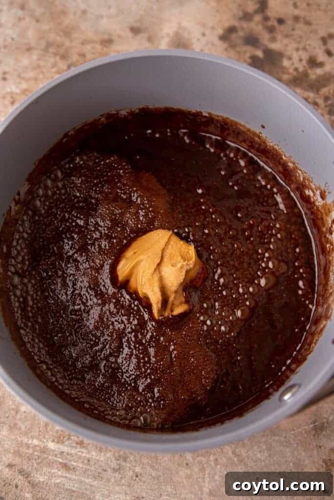 The chocolate mixture coming to a boil in a saucepan, showing active bubbling.