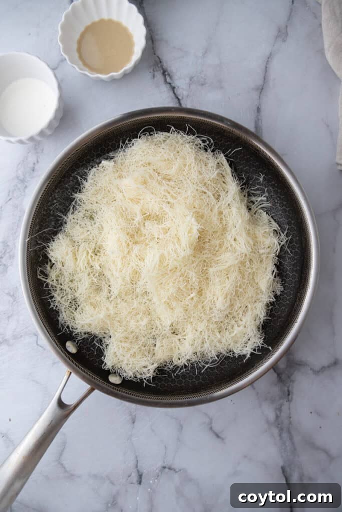 Shredded kataifi dough cooking in melted butter in a skillet.