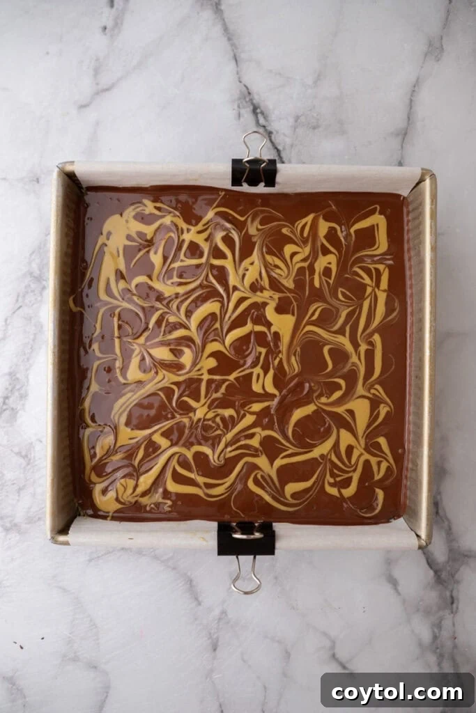 A finished Dubai chocolate brownie in the pan showing swirls of chocolate and pistachio spread, ready to be chilled.