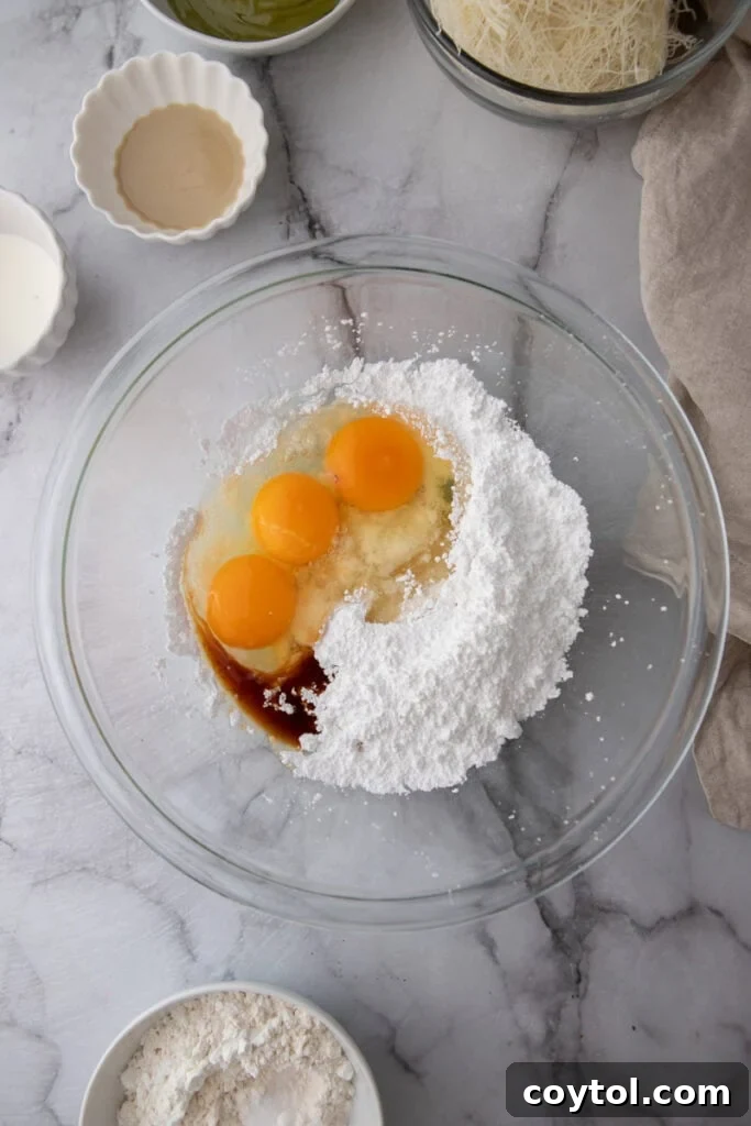Eggs, sugars, and vanilla extract in a bowl, ready to be beaten.