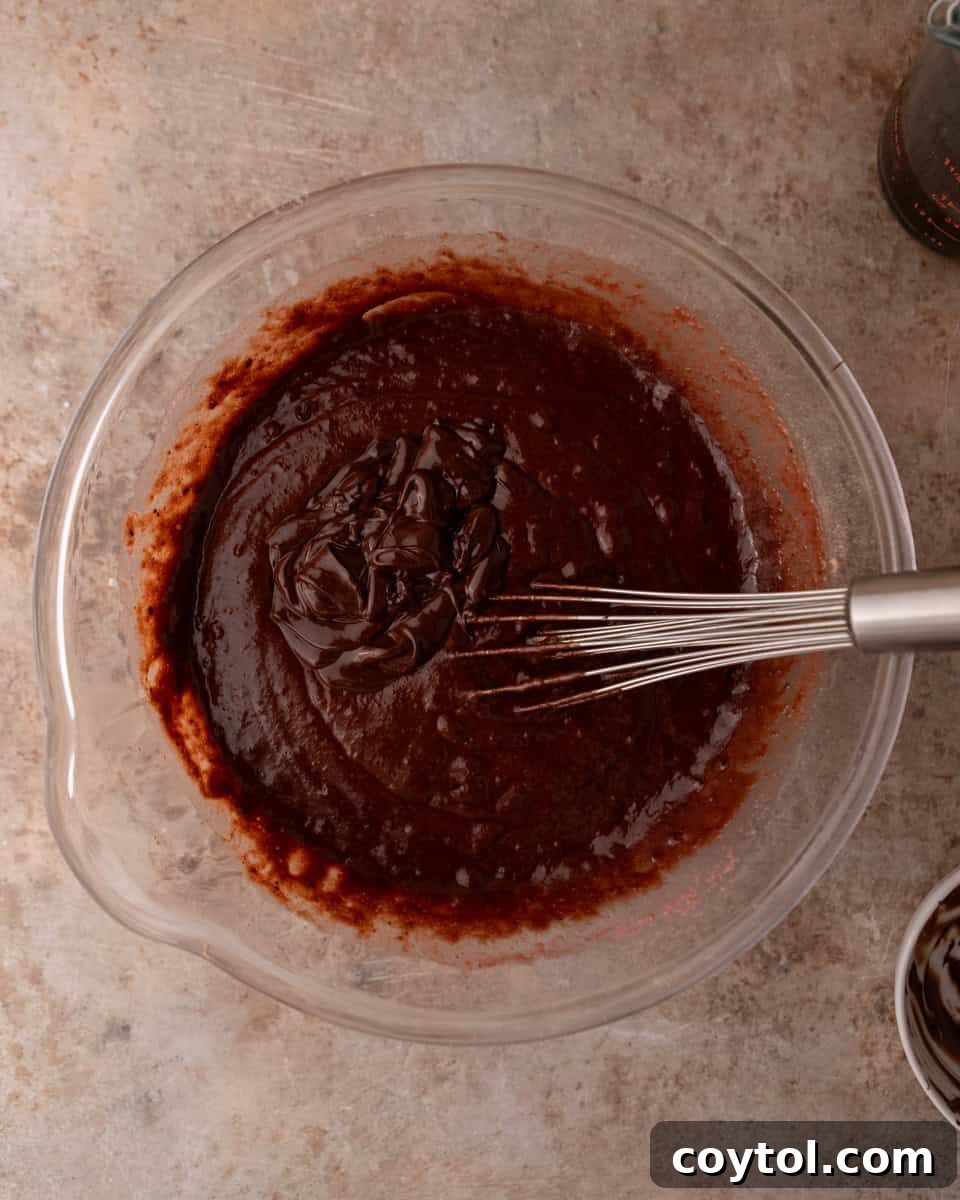 Smooth chocolate cake batter being whisked in a bowl