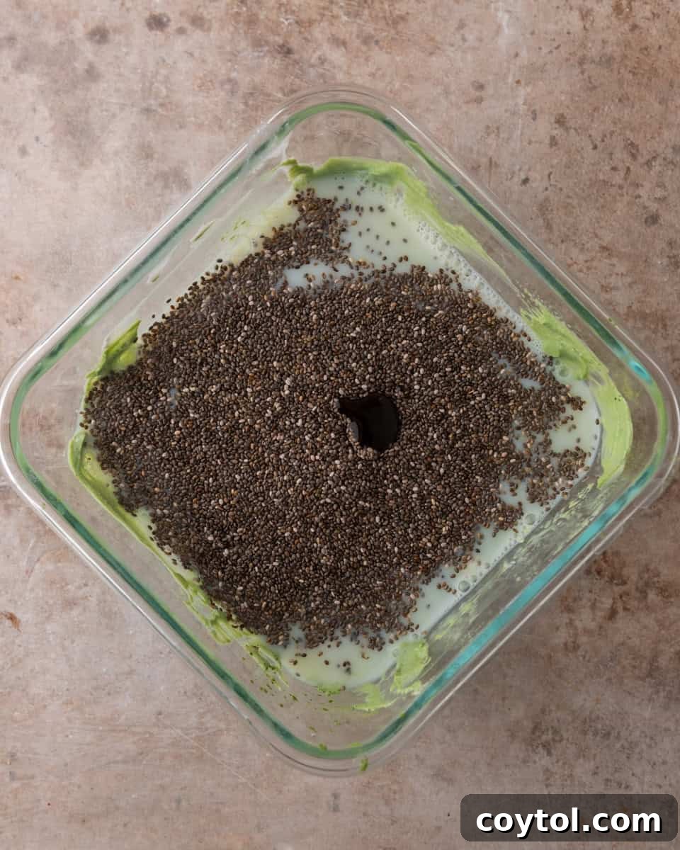 Chia seeds being carefully added to the vibrant matcha and milk mixture in a bowl before the crucial chilling phase.
