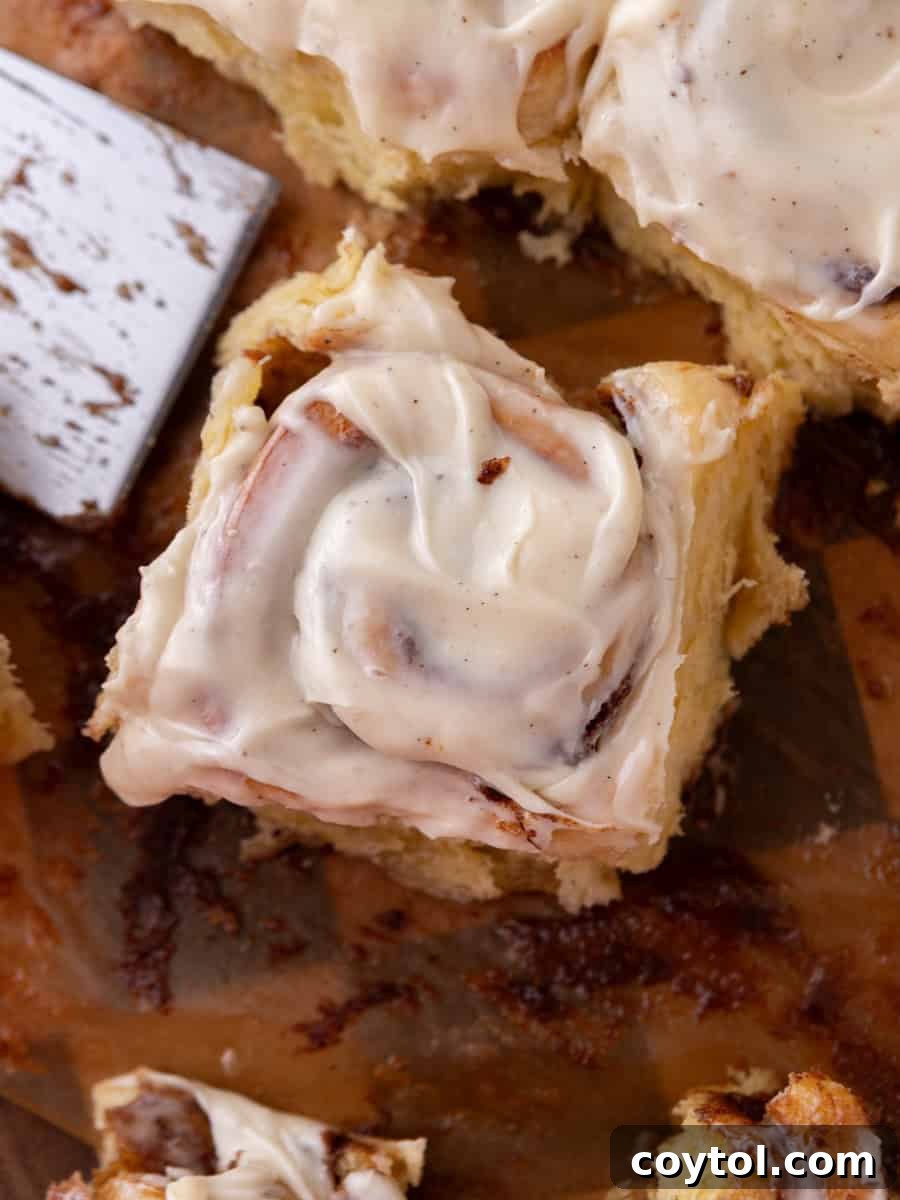 Gooey brioche cinnamon roll with cream cheese frosting lifted from a baking pa