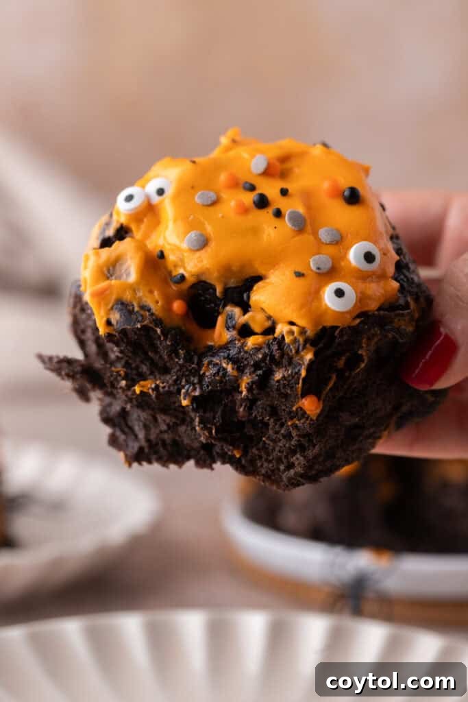 Black cocoa Halloween cinnamon roll with orange frosting and candy eyes