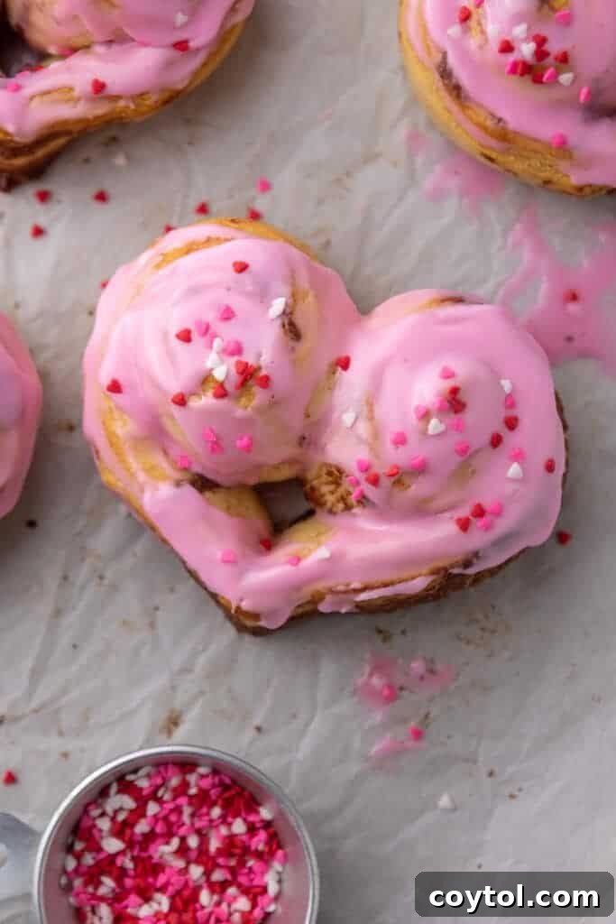 Heart shaped cinnamon rolls with pink frosting and Valentine sprinkles
