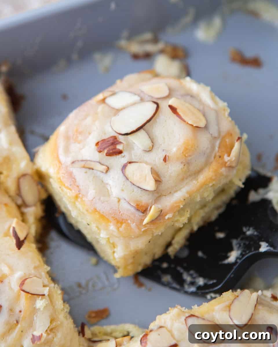 Almond croissant cinnamon roll topped with glaze and toasted sliced almonds