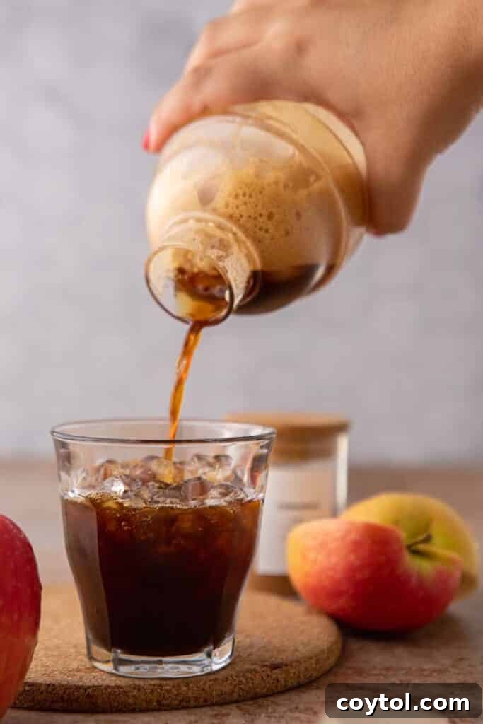 Unlock Starbucks Flavors: 65+ Beloved Recipes You Can Make 14 Pouring homemade Starbucks apple crisp oatmilk shaken espresso from a cocktail shaker over ice with fresh apples