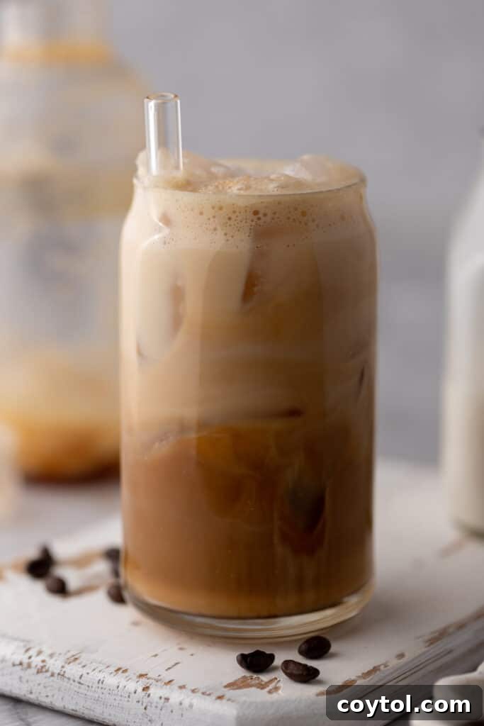 Unlock Starbucks Flavors: 65+ Beloved Recipes You Can Make 7 Homemade Starbucks iced caramel latte in a glass with a straw and coffee beans on the side