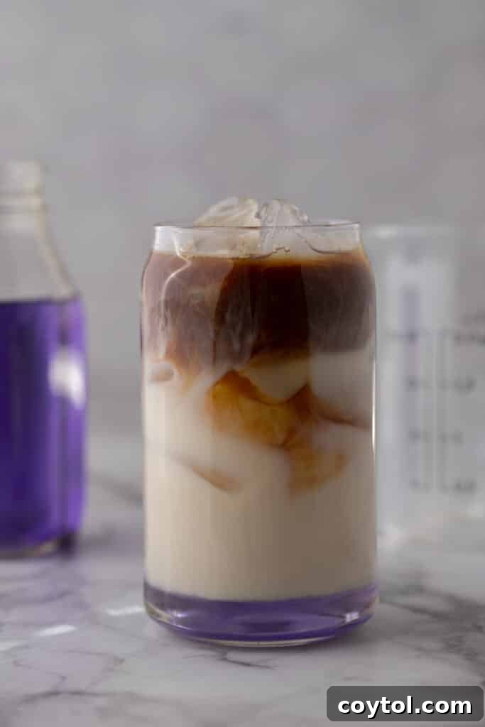 Unlock Starbucks Flavors: 65+ Beloved Recipes You Can Make 9 Homemade Starbucks iced lavender oatmilk latte with espresso swirling into milk with a purple lavender syrup bottle