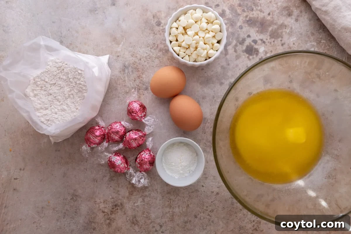 Ingredients laid out on a marble surface including cake mix, eggs, butter, white chocolate chips, cornstarch, and Lindt strawberry truffles