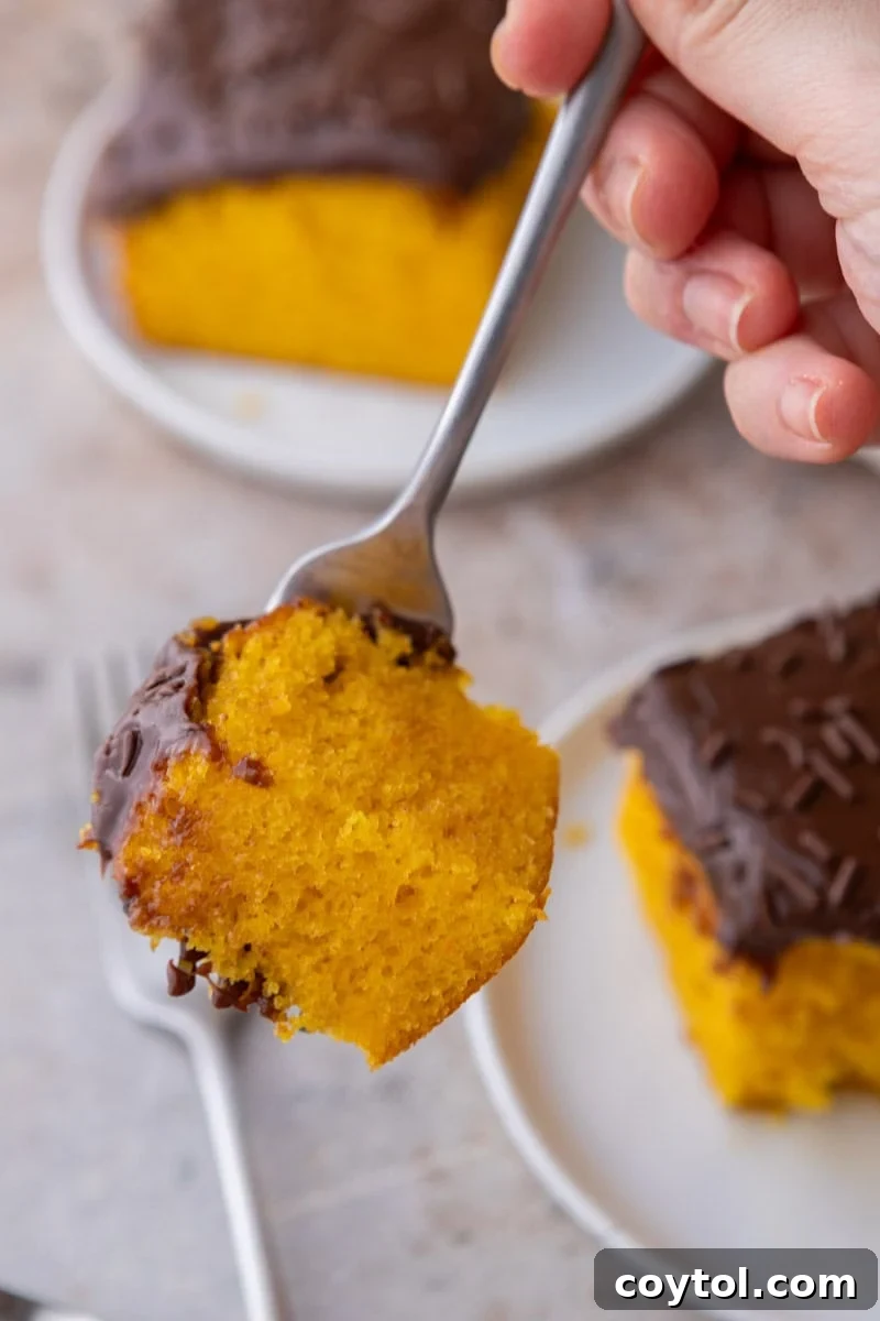 Vibrant Brazilian Carrot Cake with Decadent Chocolate Glaze 15 A fork holding a delectable bite of vibrant orange cake with glistening chocolate glaze, showing the soft, moist crumb up close and in tempting detail.