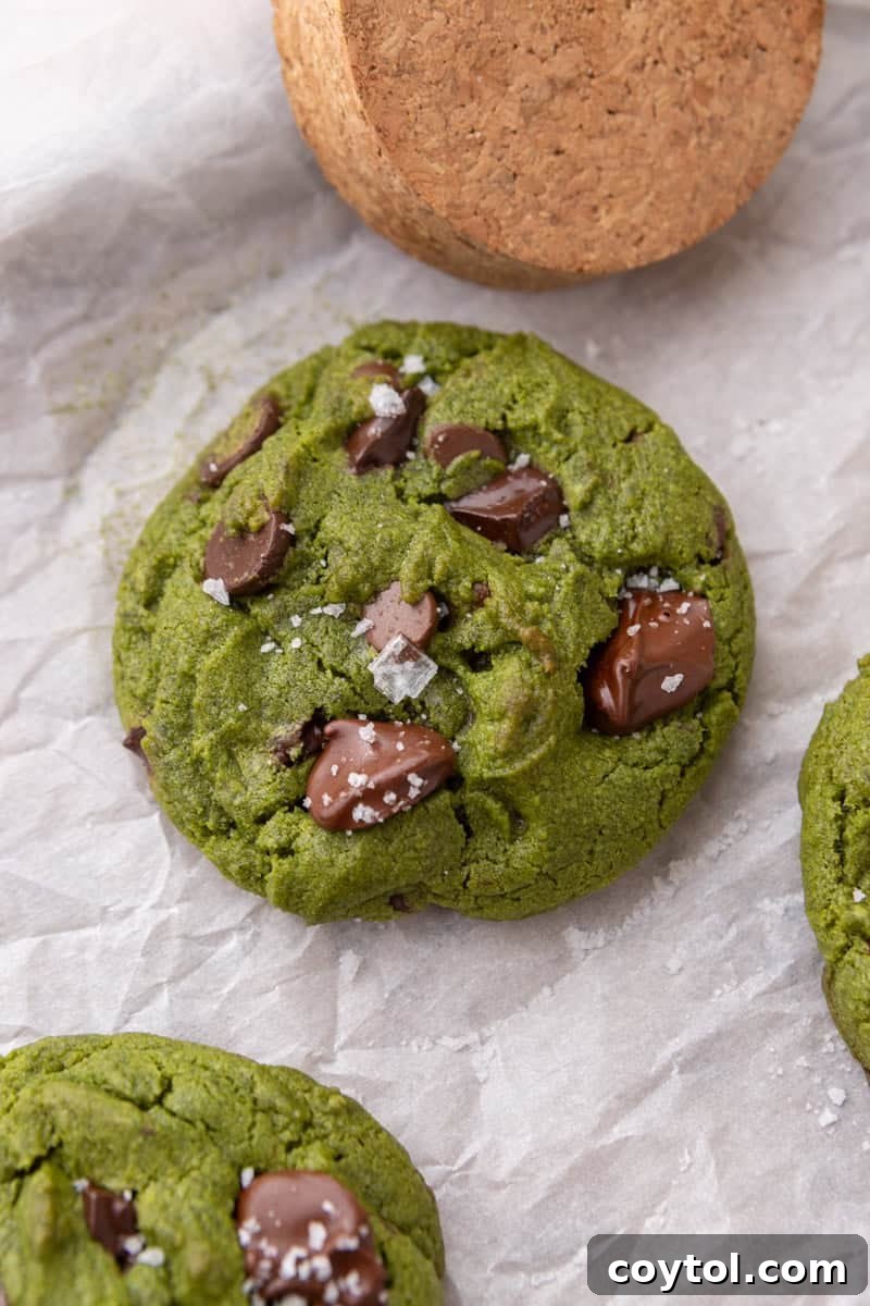  Close-up overhead of a baked matcha cookie topped with melted chocolate chunks and flaky sea salt