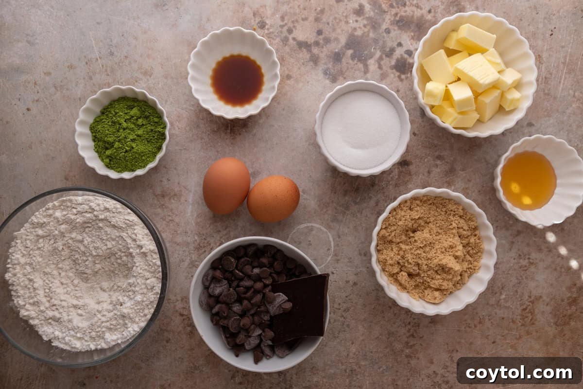 Ingredients for matcha cookies measured out in white bowls including flour, matcha powder, butter, sugars, eggs, chocolate chips, honey, and vanilla
