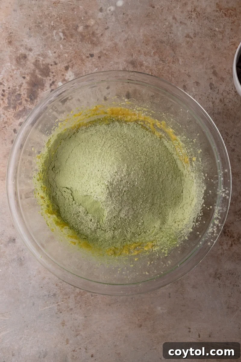  Matcha flour mixture added to the wet ingredients in a glass mixing bowl before combining
