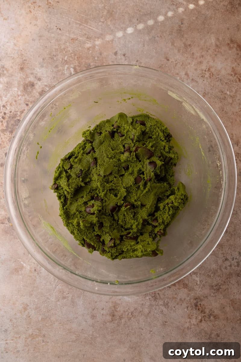 Finished matcha cookie dough with chocolate chips mixed throughout in a glass bowl
