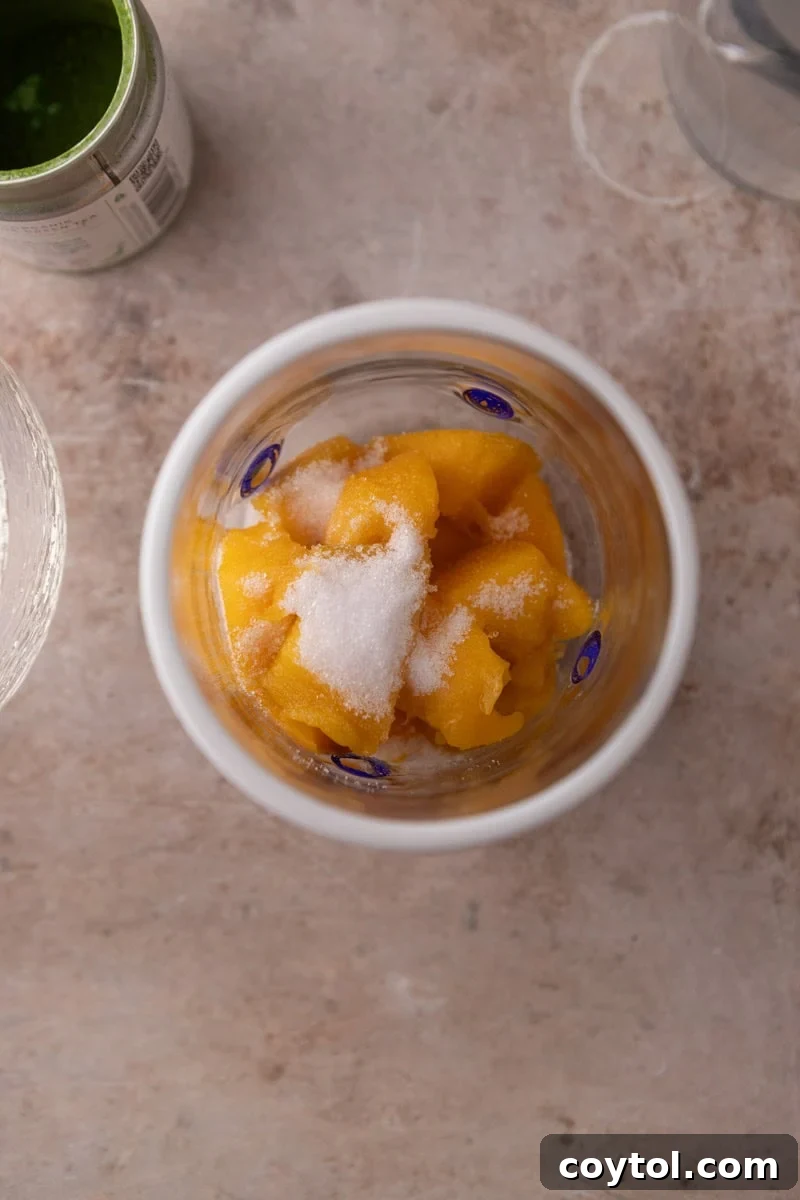 Fresh Mango Matcha Coconut Water Delight 4 fresh mango chunks and sweetener in a wide mouth glass before blending with an immersion blender