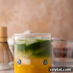iced mango matcha drink with coconut water in a glass with golden mango and green matcha layers