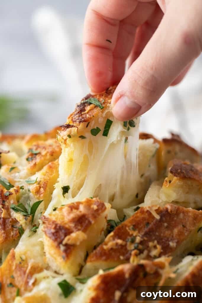 Golden Gooey Garlic Bread Pull Apart Perfection 2 Hand pulling apart a piece of cheesy sourdough garlic bread with melted mozzarella stretching into long strands