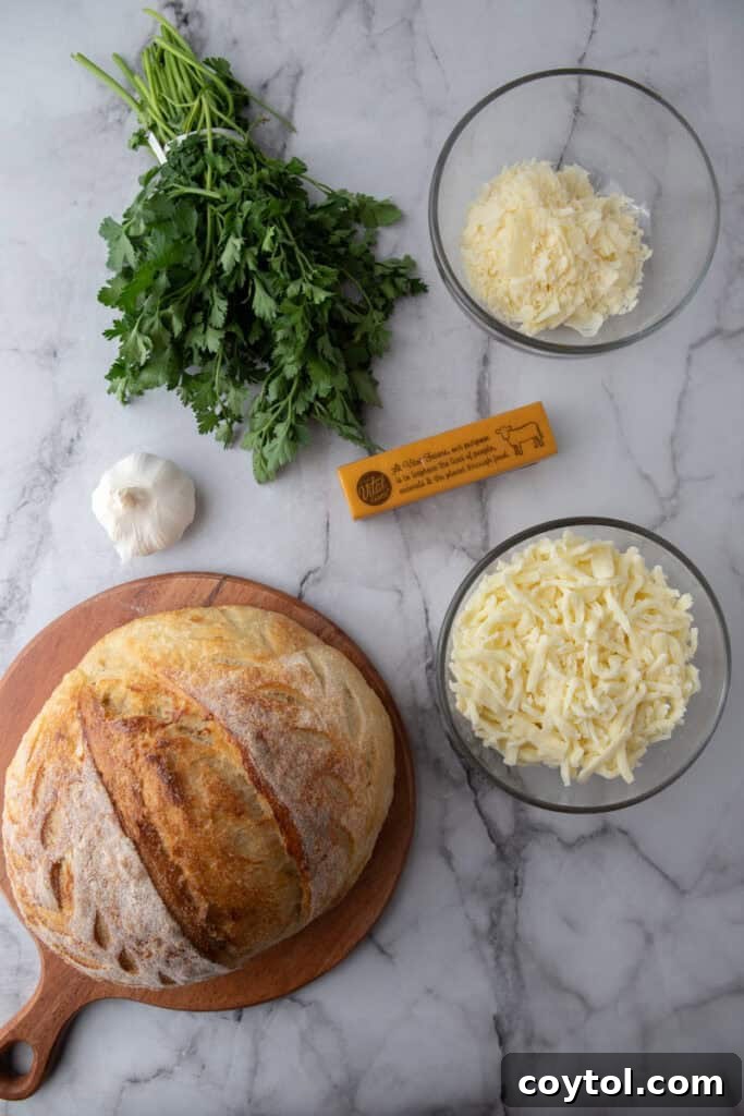 Golden Gooey Garlic Bread Pull Apart Perfection 3 Key ingredients for garlic bread, including a rustic sourdough loaf, blocks of mozzarella and parmesan, fresh garlic cloves, unsalted butter, and fresh parsley, neatly arranged on a counter.