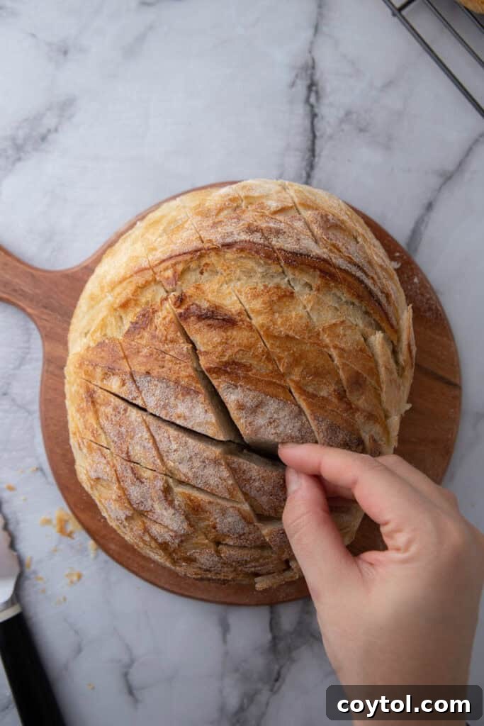 Golden Gooey Garlic Bread Pull Apart Perfection 5 A sourdough loaf expertly cut in a crosshatch pattern on a cutting board, creating deep pockets and ready for the next step of stuffing.