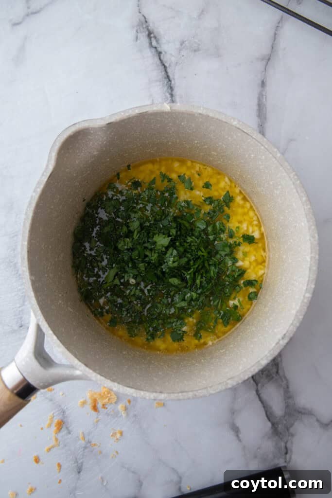 Golden Gooey Garlic Bread Pull Apart Perfection 6 Melted garlic butter with vibrant fresh chopped parsley in a small saucepan, stirred and ready to be applied to the bread.