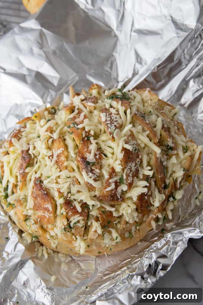 Golden Gooey Garlic Bread Pull Apart Perfection 8 Close-up of an unbaked sourdough garlic bread, visibly topped and stuffed with shredded mozzarella and parmesan, glistening with infused butter, ready for the oven.