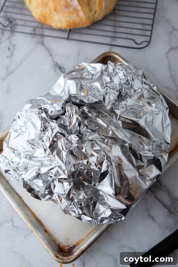 Golden Gooey Garlic Bread Pull Apart Perfection 9 Garlic butter bread, gently covered loosely with aluminum foil on a baking sheet, strategically prepared for its initial bake in the oven.