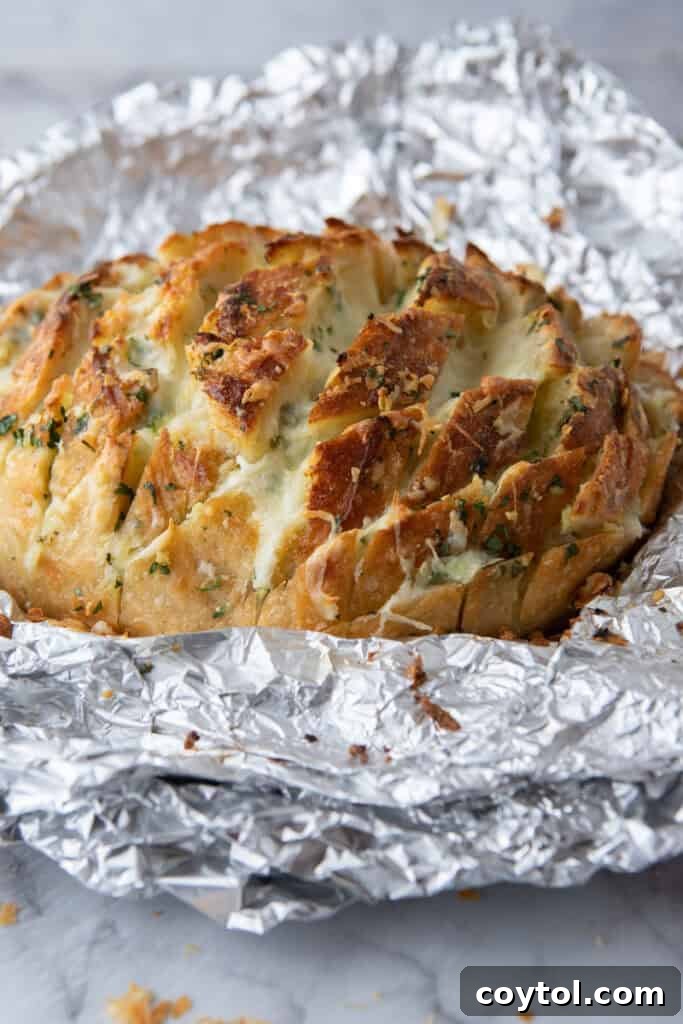 Golden Gooey Garlic Bread Pull Apart Perfection 10 Freshly baked pull-apart garlic bread with perfectly melted cheese still nestled in its foil, looking golden, bubbly, and incredibly inviting straight from the oven.