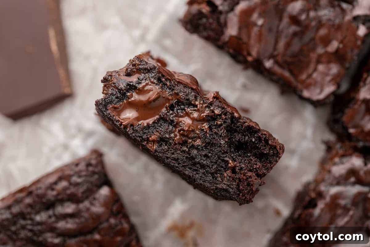 A perfectly portioned small batch brownie featuring a melted chocolate chunk center on parchment paper, beautifully revealing its ultra-fudgy interior texture, ideal for two.
