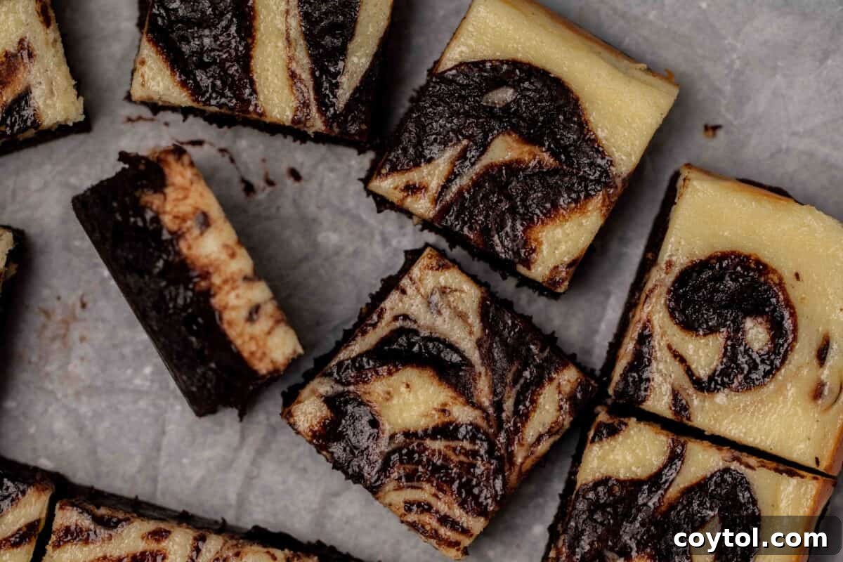 Exquisite cream cheese cheesecake brownies, sliced into perfect squares, showcasing the beautifully marbled swirl pattern of tangy cream cheese and rich, fudgy chocolate brownie, with one piece gracefully tilted on its side, seriously addictive.