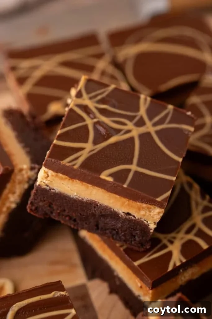 Decadent Buckeye brownies, showcasing three distinct, rich layers: a fudgy brownie base, a smooth peanut butter filling, and a glossy chocolate ganache finish with an elegant peanut butter drizzle on top, tastes even better.
