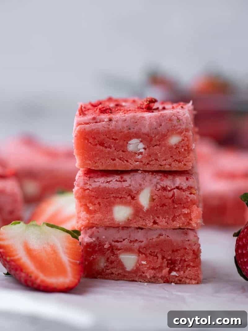 Vibrant pink strawberry cake mix brownies, neatly sliced into squares, with one piece tilted to showcase its fudgy, bright pink interior dotted with melted white chocolate chips, a Valentine's Day favorite.