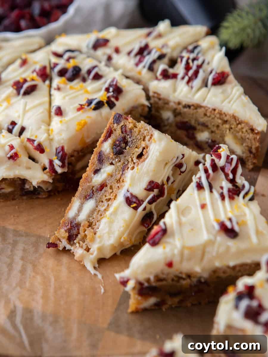 Copycat Starbucks cranberry bliss bars, elegantly sliced into triangles on parchment paper, showcasing their chewy blondie base adorned with cream cheese frosting, dried cranberries, and fragrant orange zest on top, better than coffee shop.