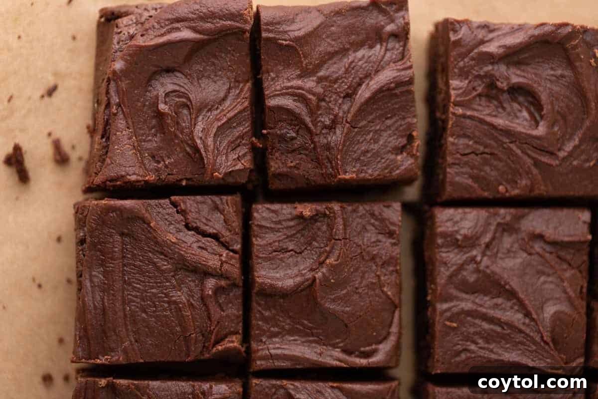 Decadent brownies, lavishly topped with thick, swirled chocolate brownie frosting, neatly sliced into squares on parchment paper, showcasing the rich, fudgy frosting layer, ready in 4 minutes.