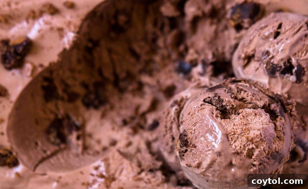 Close up of luscious scoops of chocolate no-churn ice cream, generously mixed with delectable brownie chunks, showcasing its creamy texture and visible brownie pieces, no ice cream maker needed.