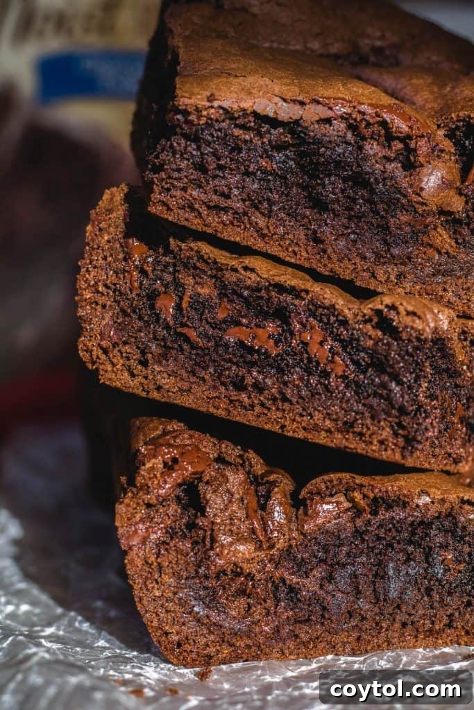 Close-up stack of three fudgy cake mix brownies, showing delicious melted chocolate pools and a dense, chewy interior, made with just 5 ingredients.