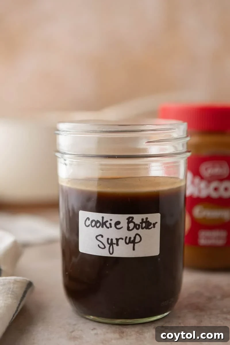 Homemade cookie butter coffee syrup in a labeled mason jar with a jar of Lotus Biscoff cookie butter in the background.