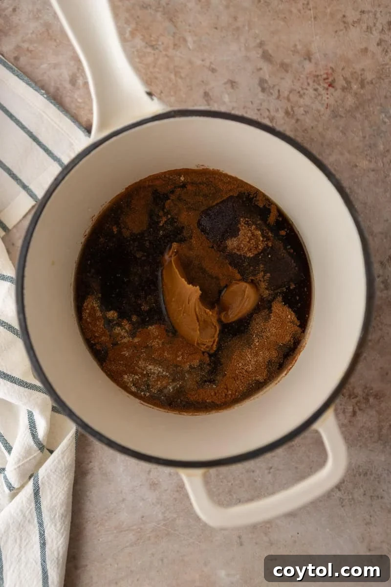 Dark brown sugar, Biscoff cookie butter, and spices added to a saucepan before cooking.