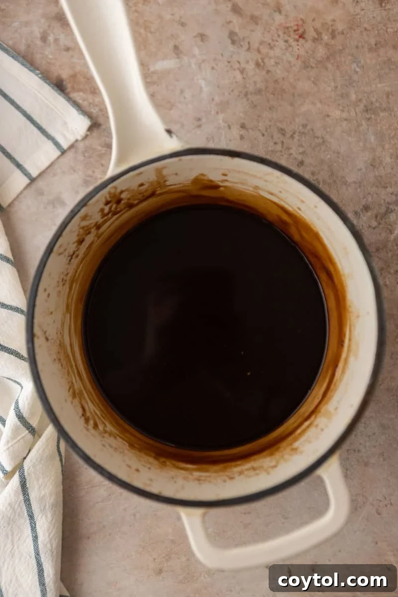 Coffee syrup after simmering in a saucepan, smooth and dark.