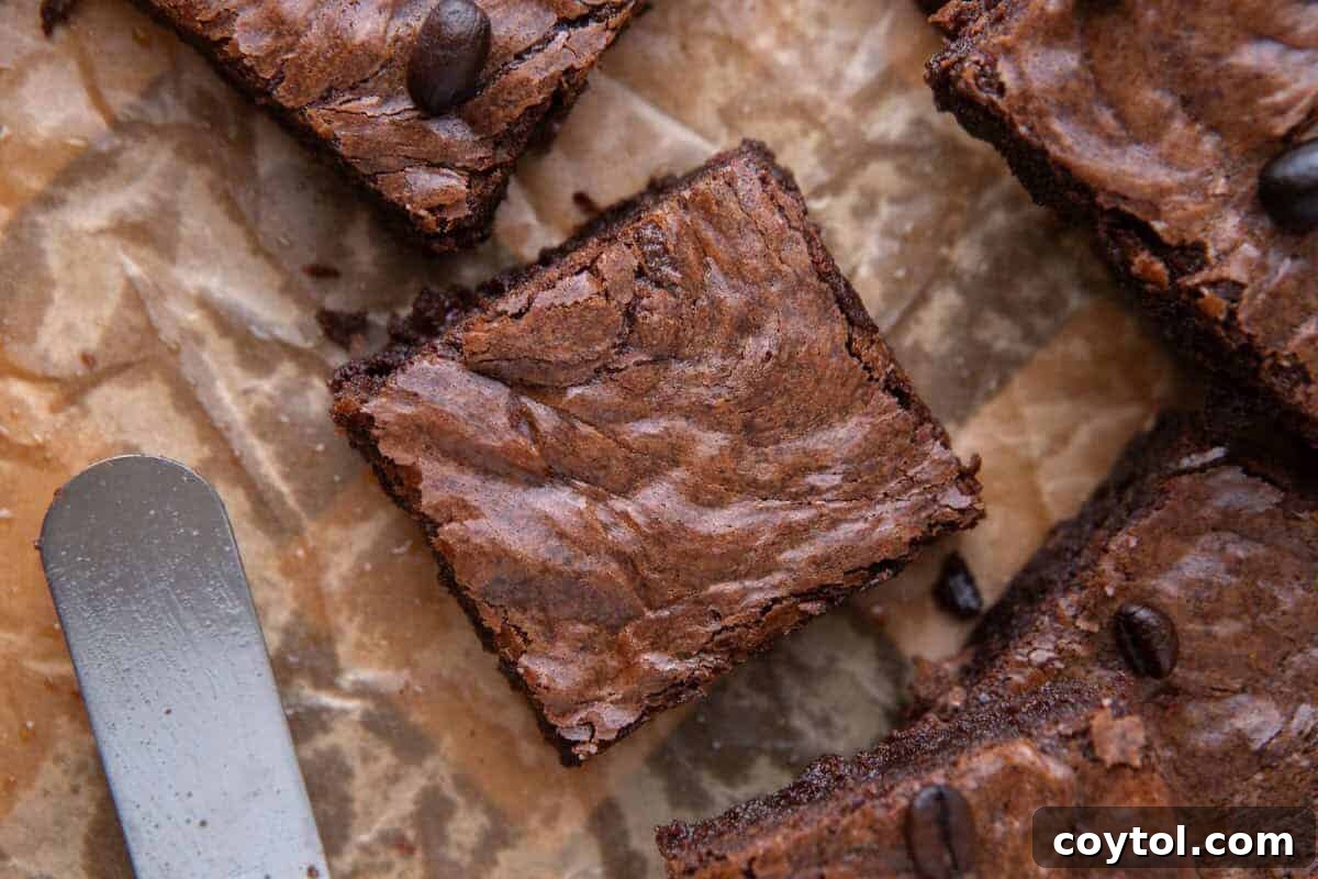 Fudgy espresso brownie square on crinkled parchment paper with an offset spatula